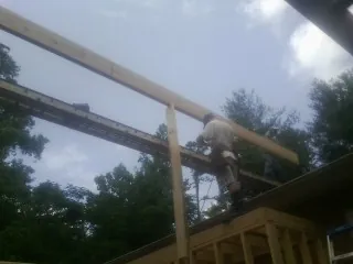 Carpenter setting a ridge beam over a new addition frame — Ice Dam Removal by Roofing Brothers in Molina