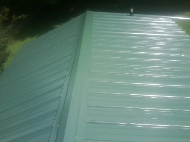 New green metal panels meeting at the ridge of a roof — Flat Roof Repair work by our crew in Molina
