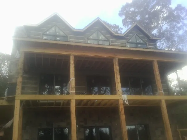 Dormers and porch framing on a large log home under construction — Roof Coating work by our crew in Molina