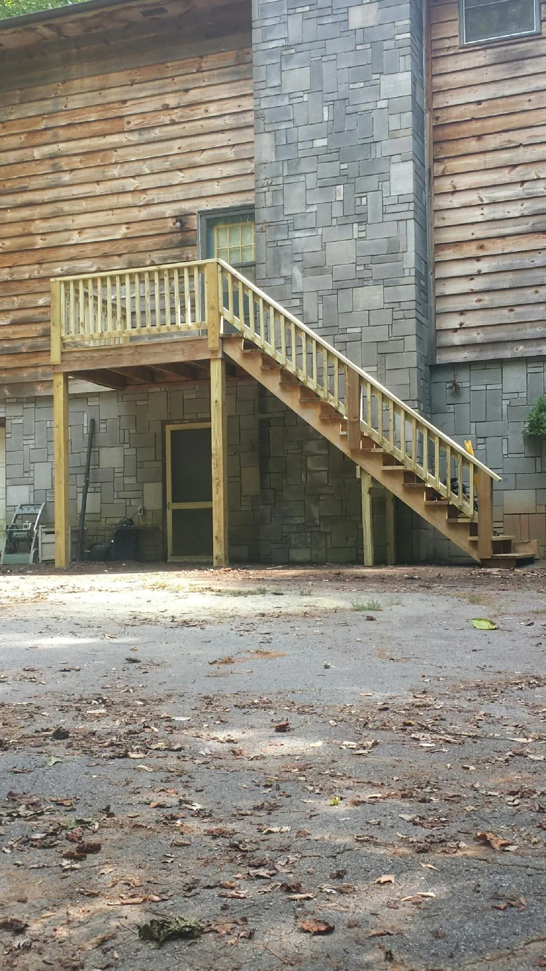 New pressure treated deck and stair landing on a log home in Molina