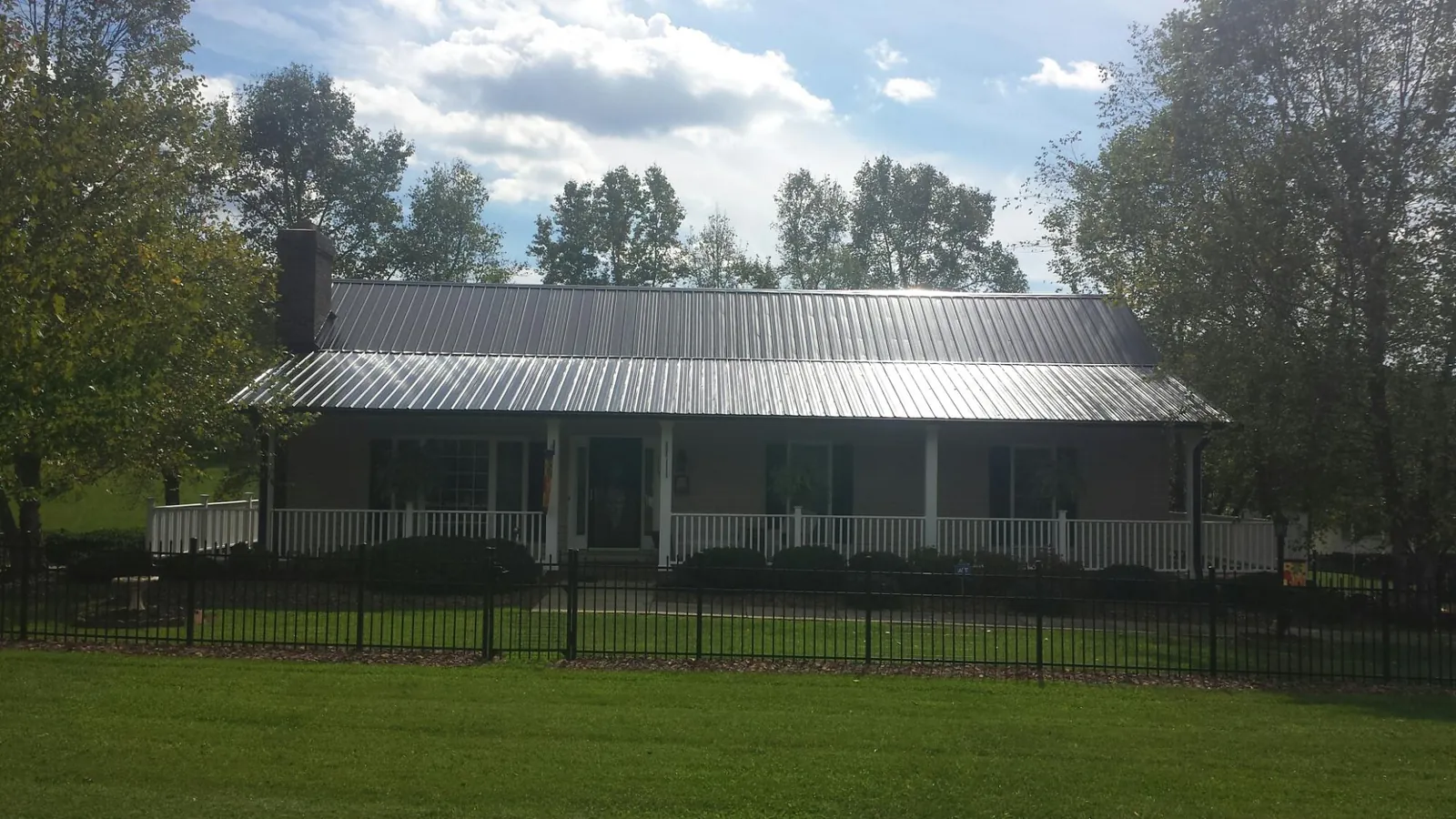 Gray metal roof on a brick ranch with a full width front porch — Gutter Guard Installation work by our crew in Molina