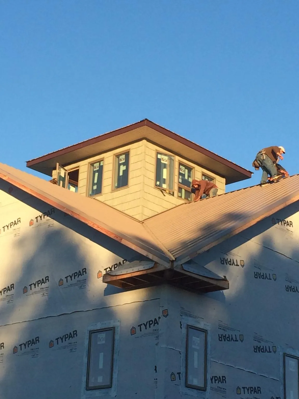 Roofers working around a rooftop cupola on a new metal roof at sunset — Roof Waterproofing in Molina by Roofing Brothers